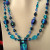 Dichroic art glass, lampworked glass and crystal beads frame a dichroic glass pendant, all in shades of cool blues and greens. Dichroic art glass, lampworked glass and crystal beads frame a dichroic glass pendant, all in shades of cool blues and greens.