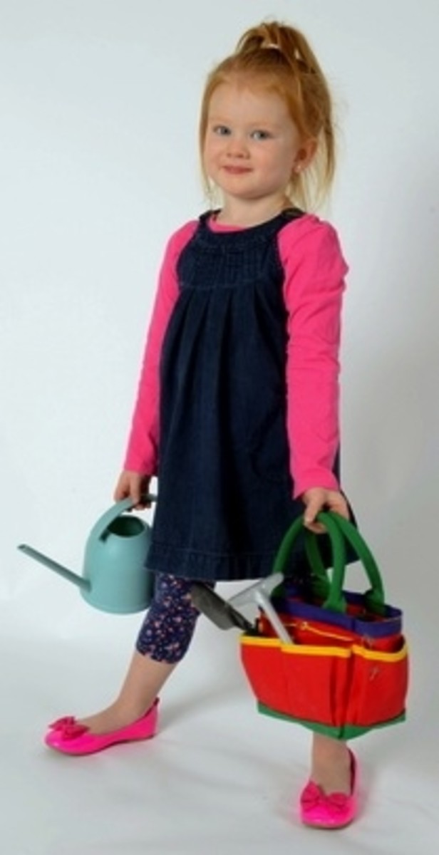 A happy gardener toting her kid-sized Garden Kit and watering can.