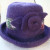 Solid purple wool yarn was used to create this felted hat. A ribbon and a rosette embellished this felted hat.