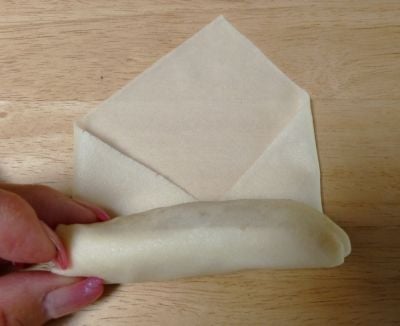 Fold the left and right corners and continue rolling snugly to the top. Seal corner with dab of water.