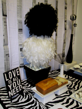 Center Back -- black and white feather topiary as a centerpiece, "Love" plaque on plate stand, milk glass vase with fanned netting