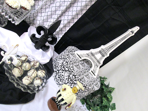 Middle Right - truffles platter on a riser covered in black fabric and the fleur de lis on white satin &amp; the jolly chef, &amp; Eiffel Tower.