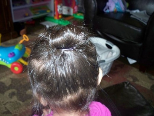 Take the remaining loose over the top of the sock bun and secure with a rubber band. I like to use rubber bands because they hold the hairstyle secure and still allow my girls to run wild without getting poked by bobby pins.Bobby pins may be a bett