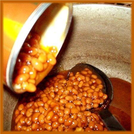 While the meat is cooking, place 3 cans of baked beans in a large pot.