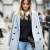 This woman is wearing a gray overcoat trench style, walking down the street with headphones and bright blue jeans. This woman is wearing a gray overcoat trench style, walking down the street with headphones and bright blue jeans.