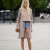 Blonde woman with light blue Daisy Dukes and a tan long jacket with a brown purse that matches her belt. Blonde woman with light blue Daisy Dukes and a tan long jacket with a brown purse that matches her belt.