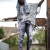 African street style of African woman wearing scarf and a dirty white blouse and tight matching pants. African street style of African woman wearing scarf and a dirty white blouse and tight matching pants.