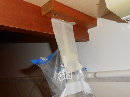 Use masking tape or other sturdy tape and attach the bag to the edge of the cabinet or other surface near where ants are entering.