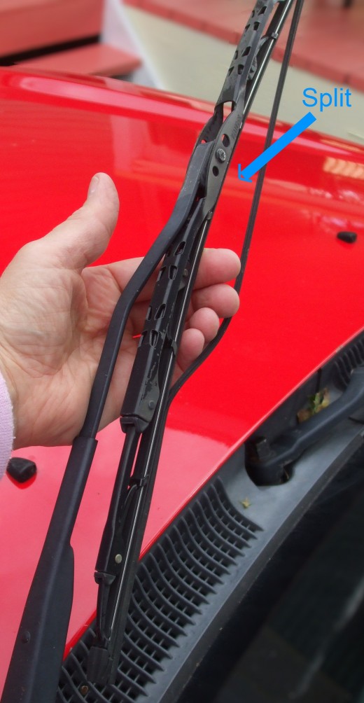 Fingers hold open the two torn parts of the rubber squeegie blade on a car windshield wiper. There should NOT be 2 parts. Fingers hold open the two torn parts of the rubber squeegie blade on a car windshield wiper. There should NOT be 2 parts.