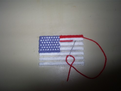 Begin cross stitching the red stripes on to the plastic mesh.