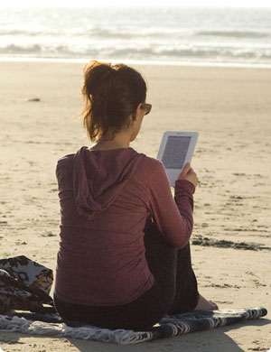 Woman Using Kindle eBook Reader at the Beach