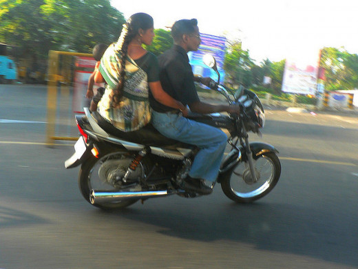 A small child being held by a pillion on the back of a motorcycle