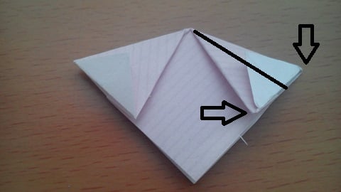 Now gently push the two edges indicated together so that the central crease pops back, and fold this back down into a diamond. See below, repeat on both sides