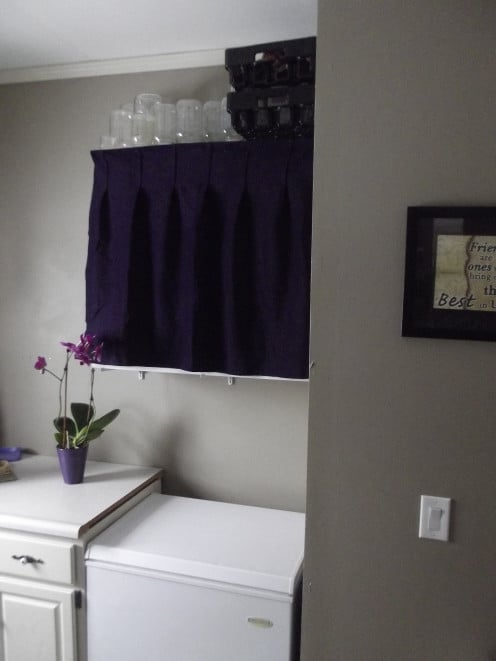 One longer pleated curtain covers all three shelves on this floating shelving unit and instantly makes this room feel less cluttered and more pleasing to be in.  