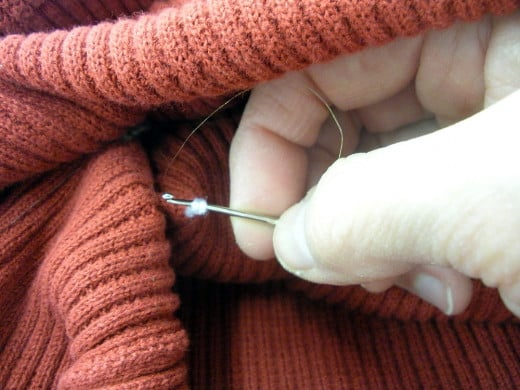 Use the crochet hook to bring the yarn through to the inside of the sweater