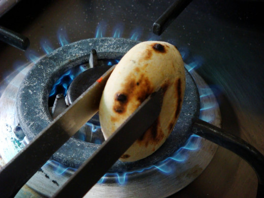 baking litti (wheat dough balls) either on a stove flame or in the burnt wood or coal ash