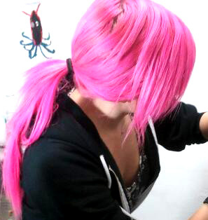 Female piercer with pink hair in a ponytail. (This is the cropped version of the photo. The larger, uncropped/unedited version can be found by clicking on the link.)