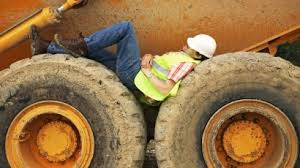 This worker looks as if he is sleeping, but in fact he is inspecting an area on this earth-mover