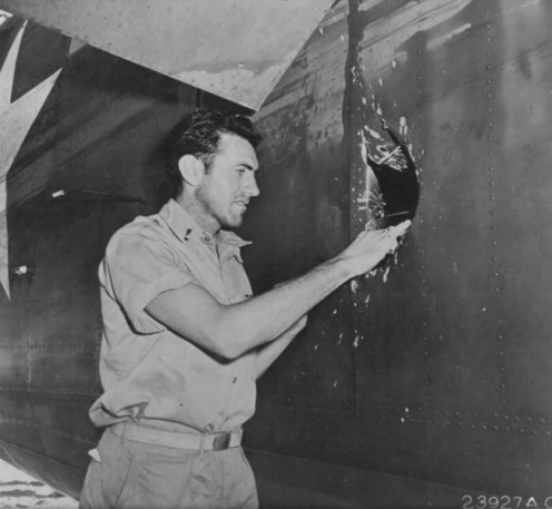 1st Lt Louis Zamperini, peers through a hole in his B-24D Liberator Superman made by a 20mm shell over Nauru, Apr 18 1943