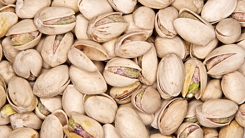Mature dried pistachios with open shells with some natural freckles on their surfaces
