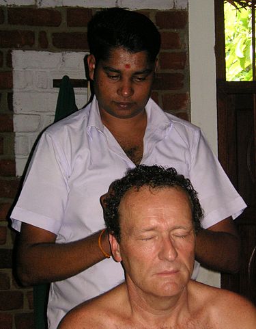 An Ayurveda practitioner applying oils using head massage.