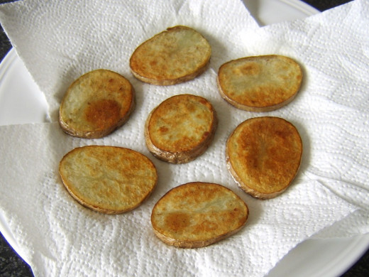 Fried potatoes are drained on kitchen paper