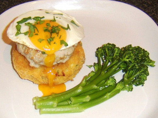 Succulent pork burger on a breaded potato cake with fried egg and broccoli
