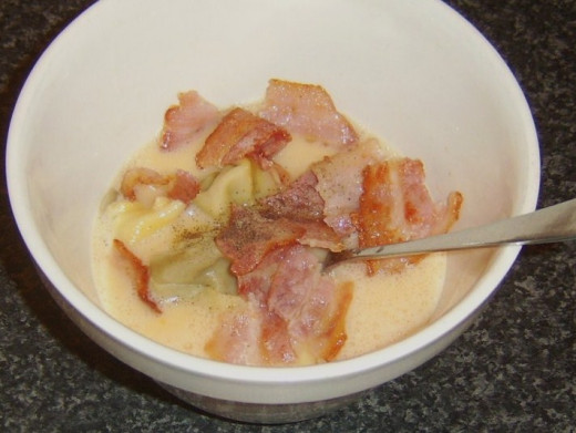 Bacon and tortelloni are added to beaten eggs