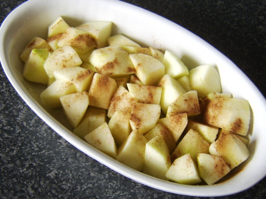 Apples are added to pie dish and scattered with cinnamon
