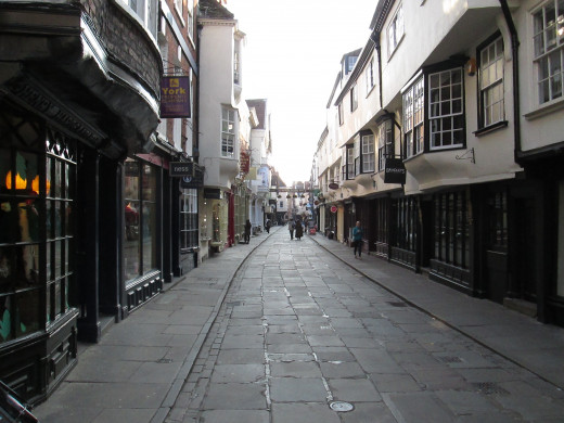 Stonegate seen from the junction with High and Low Petergate. 'Ye Old Starre Inn' is accessed through a passageway on the right below a banner that spans the street that bears its name