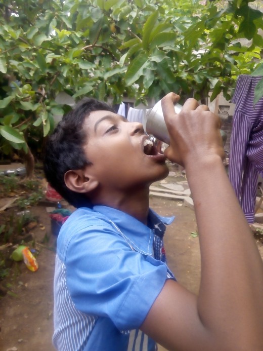 Manindranath,a child from India is feeling uncomfortable with 42 degree Celsius temperature and is trying to get relief with the help of a glass of water.