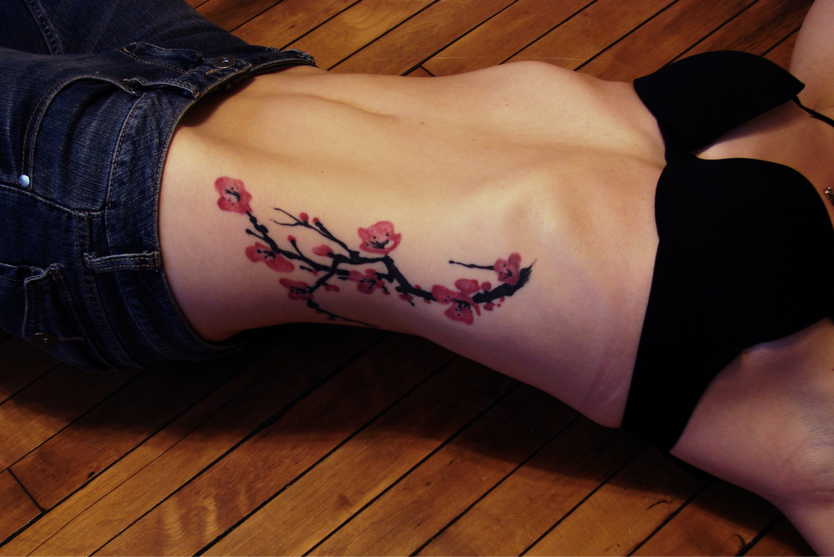 Cherry blossom branch tattoo on side.