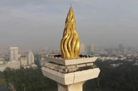Monas, topped by a flame covered with gold foil.