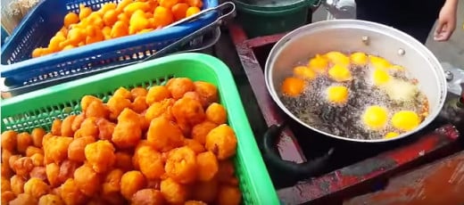 A screenshot of a street vendor deep-frying battered quail eggs for one customer. It's so delicious when served while hot. You then dipped them to a container of sweet and spicy sauce for flavor and eat. So yummy that you'll be asking for more.