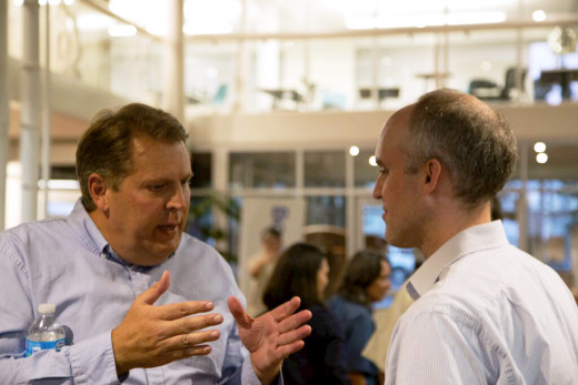 A launch party attendee (left) engages in discussion with CrowdSchool co-founder and CEO Peter Glenn (right)