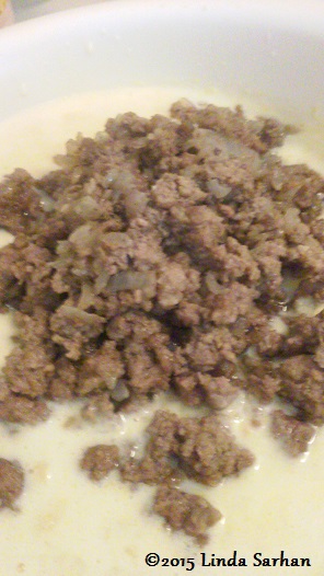 Adding ground beef mixture to corn muffin mix.