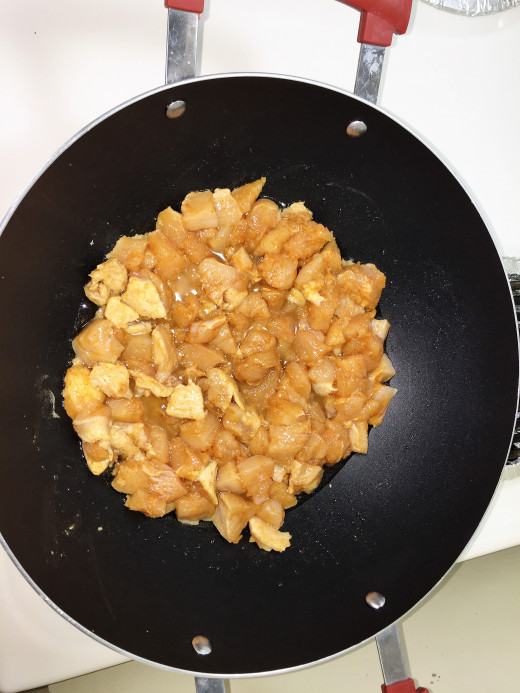 Add chicken pieces to the heated oil in the wok.