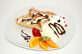 Pancakes topped with chocolate sauce, cream and fruit