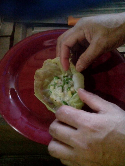 Wrapping the pili nut mixture in boiled cabbage leaves. Photo Source: Ireno Alcala