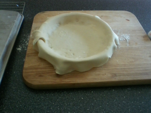 Pie crust rolled out and in glass pie pan or pie plate, with excess to crimp edges.
