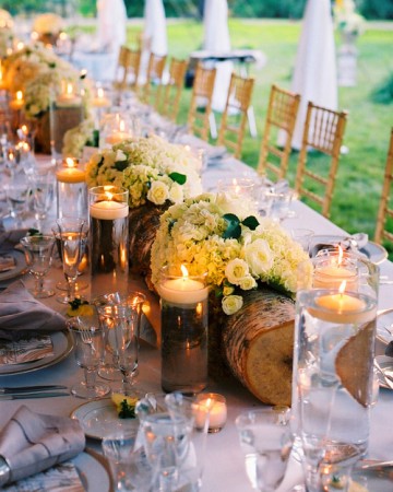 Recycled logs hallowed out with plants or flowers set in glass rectangular vases are a perfect touch for a rustic wedding