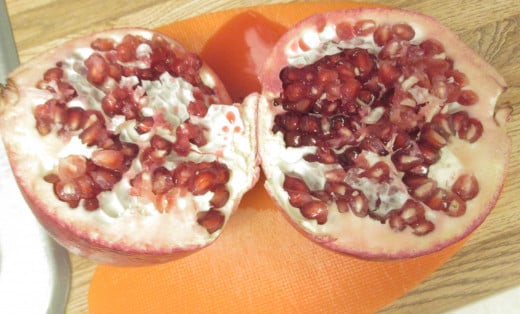 The pomegranate is divided in half to display the beautiful arils, which are filled with fruit juice and the seeds.
