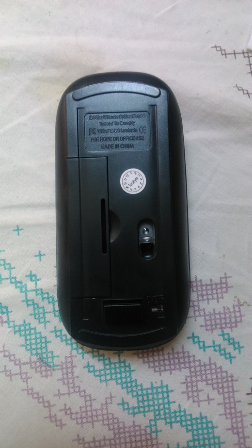 Rear view of the mouse showing the receiver inserted in its slot and the on-off switch at the right bottom corner. There is a slot for the single AA battery