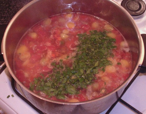 Beef pieces and chopped parsley are added to the simmering soup