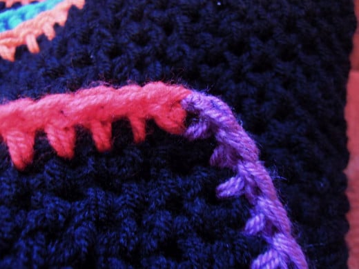 Use the tail of yarn to stitch the final purple stitch to the first red stitch and join the edging into a continuous row. 