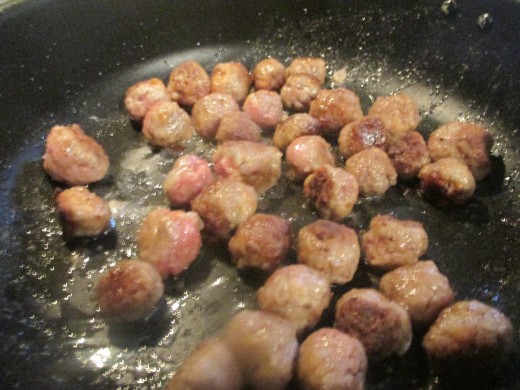 Meatballs browning in pan.