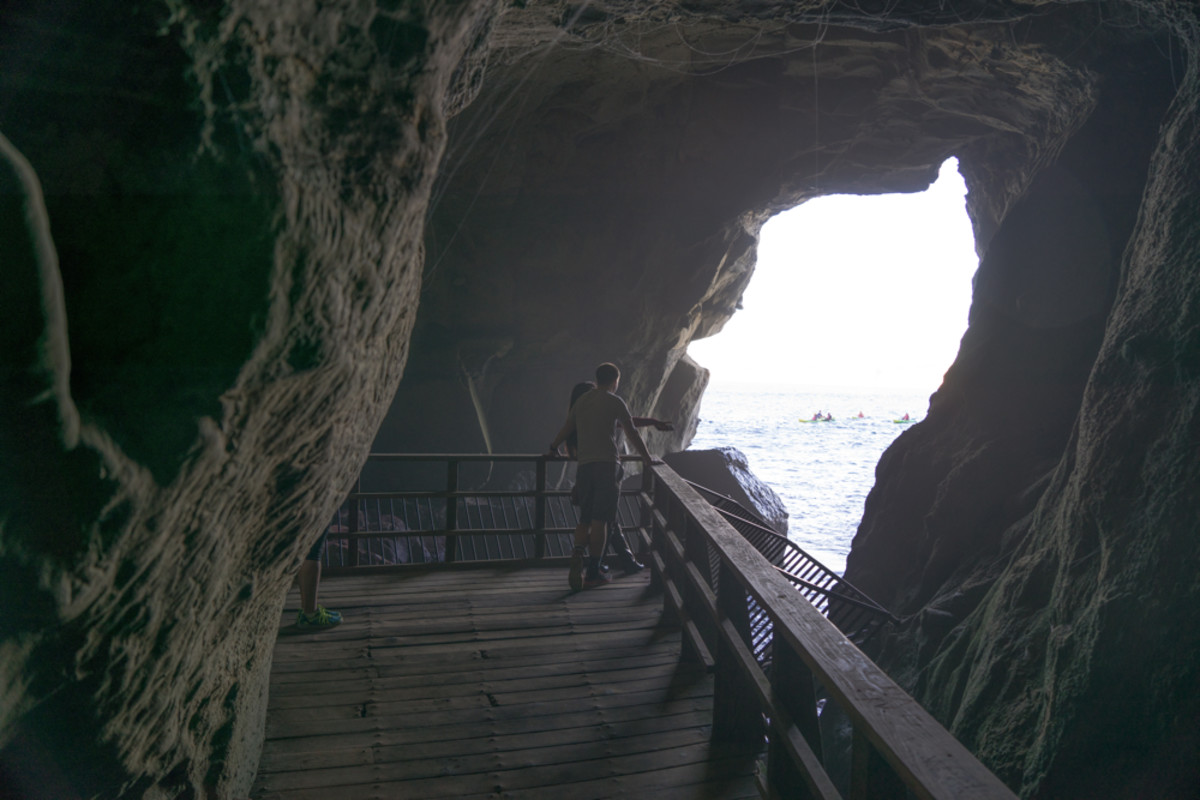 Kayak tour guests look in at tourists who have climbed down the stairs to Sunny Jim Cave in La Jolla.