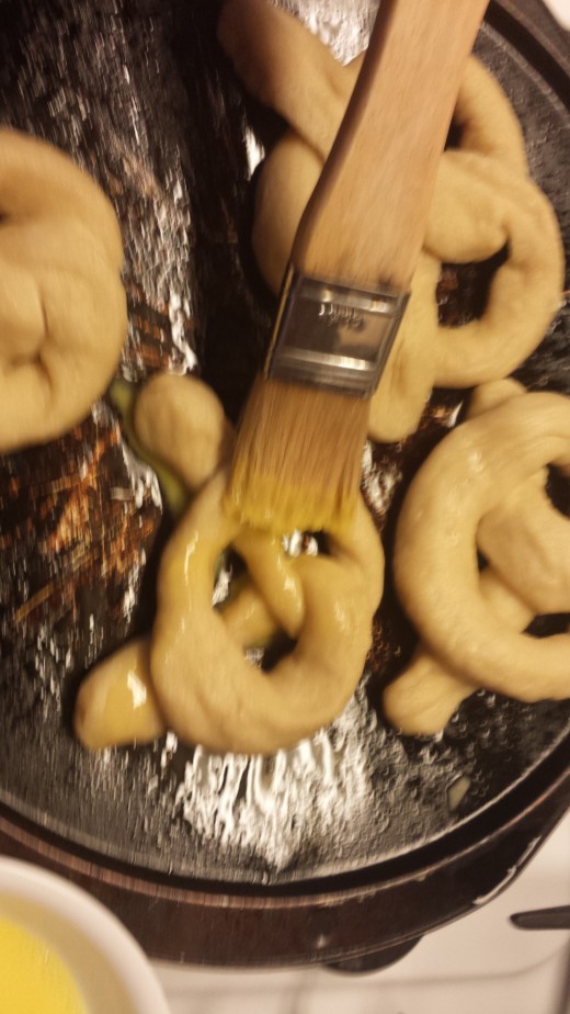 Place the boiled pretzels on a cookie sheet. I usually use parchment paper, but was out of it today, so I made due with a lightly greased pizza pan. Coat the pretzels with a wash made from beating 1 large egg yolk and 1 tbs of water.