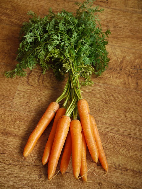 This image shows several carrots. The green tops on carrots are edible, and may be eaten as well as the orange root part.