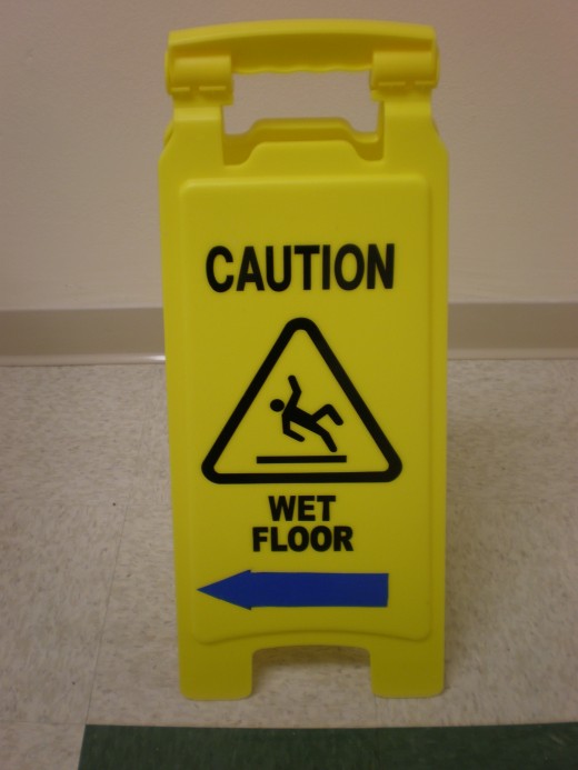 "A portable plastic sign warning of a wet floor that has recently been mopped."